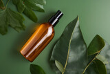 Body spray in amber glass cosmetic bottle, loofah, eucalyptus leaves on green background. SPA natural organic beauty product packaging design, branding. Beauty salon banner mockup. Flat lay, top view.