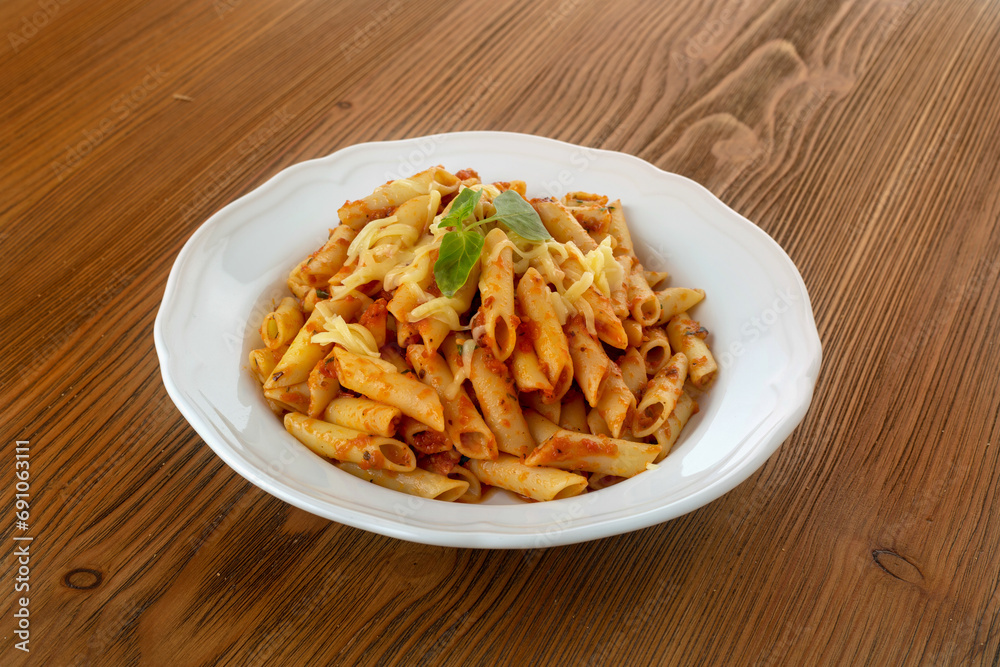 Pasta with chili sauce served in dish isolated on wooden table side view of arabic food