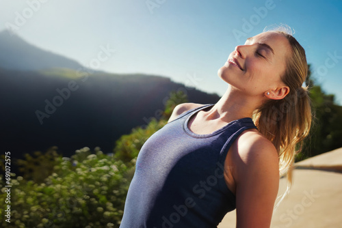 Young woman in pink sports top, enjoying sunny day, eyes closed, tilting head back in relaxation, happiness and contentment