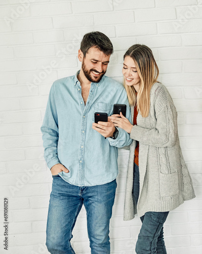 Happy young couple having fun using smartphone  during oline video call conversation or shopping or using an app at home photo
