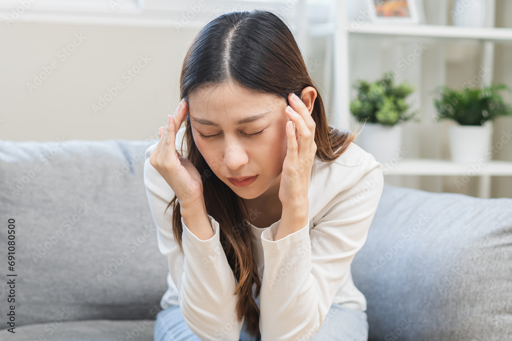 Dizzy asian young woman, girl headache or migraine pain suffering from vertigo while sitting on couch in living room at home, holding head with hand, health problem of brain or inner ear not balance. Dizzy asian young woman, girl headache or migraine pain suffering from vertigo while sitting on couch in living room at home, holding head with hand, health problem of brain or inner ear not balance.