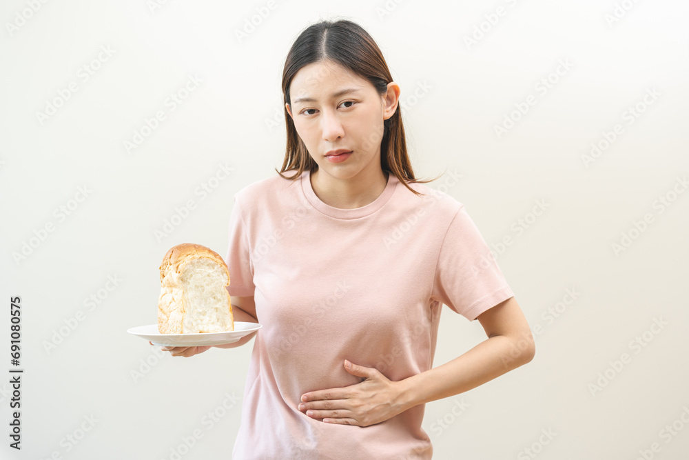 Gluten allergy, asian young woman hand holding, refusing to eat white loaf slice on plate in breakfast food meal at home, girl having a stomach ache. Gluten intolerant and Gluten free diet concept. Gluten allergy, asian young woman hand holding, refusing to eat white loaf slice on plate in breakfast food meal at home, girl having a stomach ache. Gluten intolerant and Gluten free diet concept.