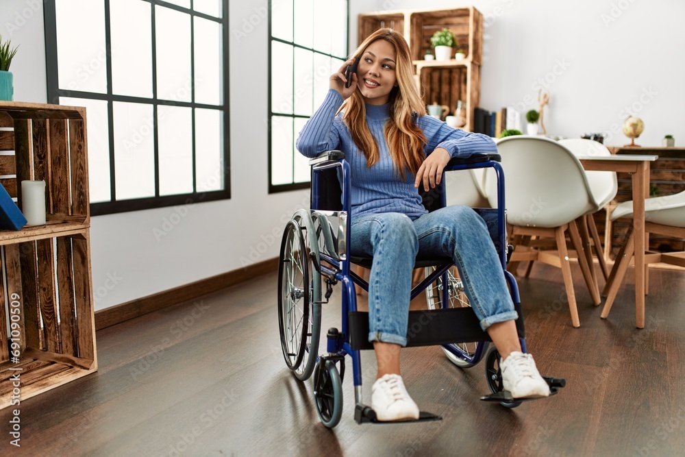 Young caucasian woman talking on smartphone sitting on wheelchair at home Young caucasian woman talking on smartphone sitting on wheelchair at home