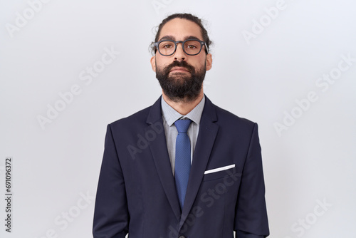 Hispanic man with beard wearing suit and tie relaxed with serious expression on face. simple and natural looking at the camera.