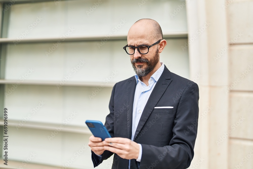 Young bald man business worker using smartphone at street Young bald man business worker using smartphone at street