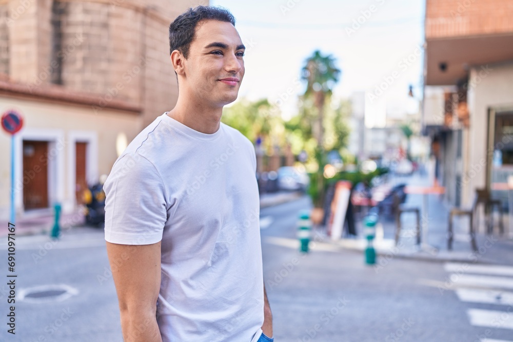 Young hispanic man smiling confident looking to the side at street