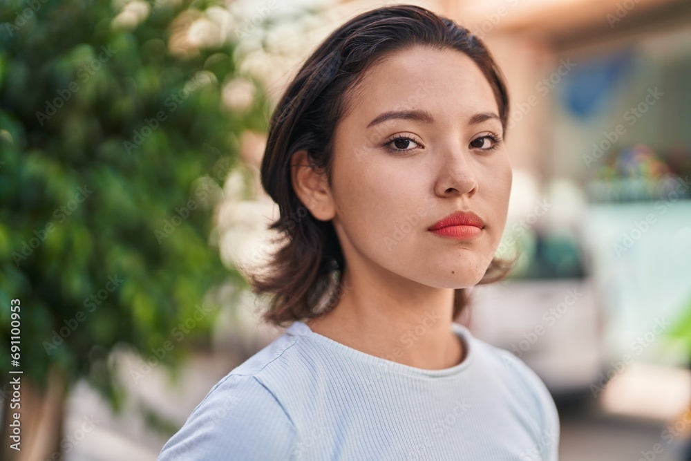 Young hispanic woman standing with serious expression at street