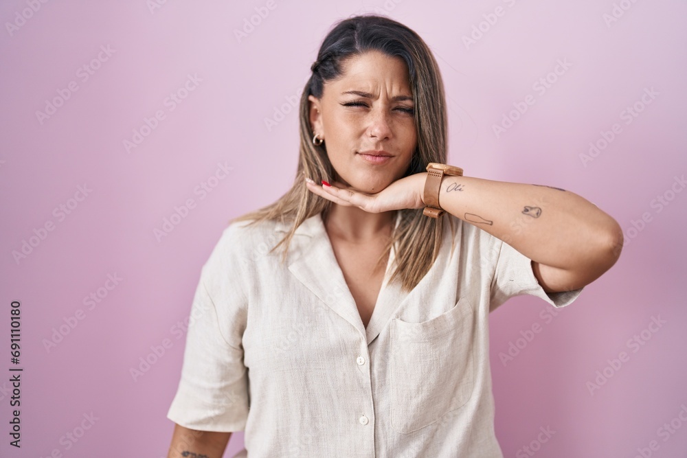 Blonde woman standing over pink background cutting throat with hand as knife, threaten aggression with furious violence Blonde woman standing over pink background cutting throat with hand as knife, threaten aggression with furious violence