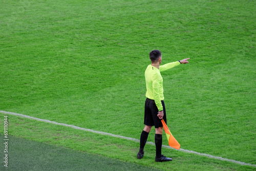 The line referee on the edge of the field with a flag in his hand indicates offside with his hand photo