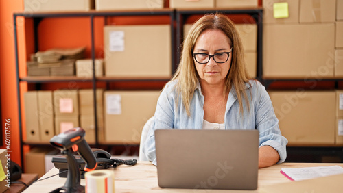 Middle age hispanic woman ecommerce business worker using laptop at office