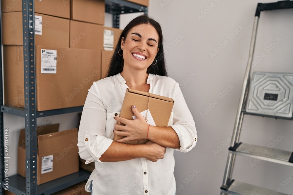 Young beautiful hispanic woman ecommerce business worker holding package at office