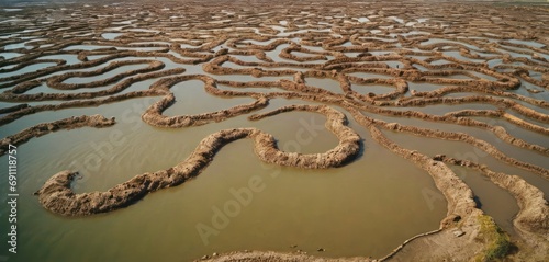 a river filled with lots of water next to a land covered in dirt and dirt mounds with a snake like structure in the middle of the water. photo