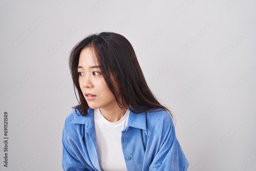 Young chinese woman standing over white background with hand on stomach because indigestion, painful illness feeling unwell. ache concept. Young chinese woman standing over white background with hand on stomach because indigestion, painful illness feeling unwell. ache concept.