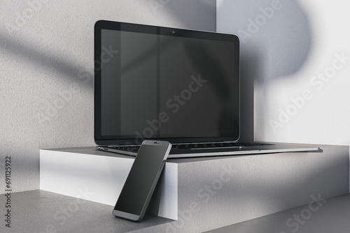 Close up of empty laptop and smartphone on gray desk. Concrete wall background and pedestal or podium. Device presentation and online education concept. Mock up, 3D Rendering.