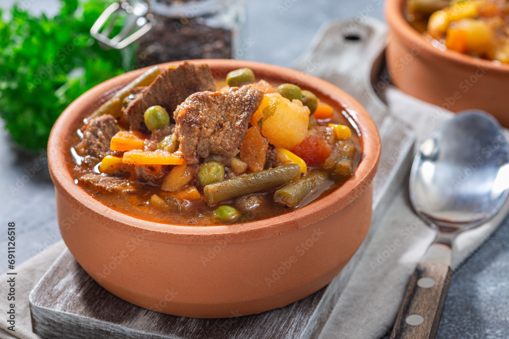 Hearty beef stew with potato, green beans, carrot, peas and corn, in ceramic bowl, horizontal Hearty beef stew with potato, green beans, carrot, peas and corn, in ceramic bowl, horizontal