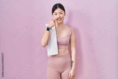 Chinese young woman wearing sportswear and towel pointing with hand finger to face and nose, smiling cheerful. beauty concept