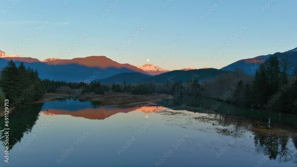 Lake surrounded by Mountains and Trees in Canadian Nature. Fall Season, Sunset Sky. Squamish, British Columbia Canada. Lake surrounded by Mountains and Trees in Canadian Nature. Fall Season, Sunset Sky. Squamish, British Columbia Canada.