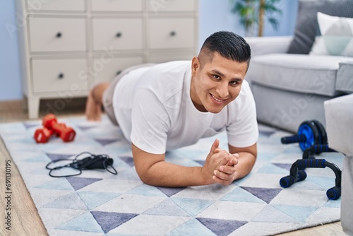 Young latin man smiling confident training core exercise at home