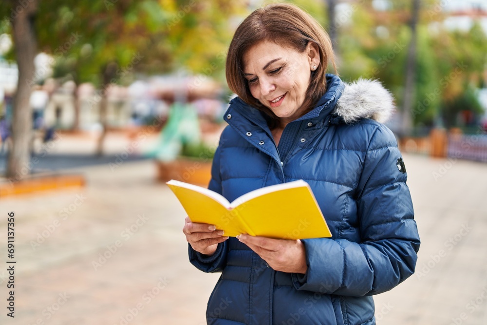 Middle age woman smiling confident reading book at park Middle age woman smiling confident reading book at park