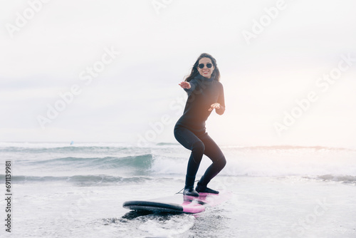 Action photo Surfer happy woman in wetsuit with surfboard go to winter surfing in ocean. Concept adventure Extreme sport.