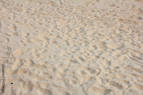 Close image of sand with several footprints marked