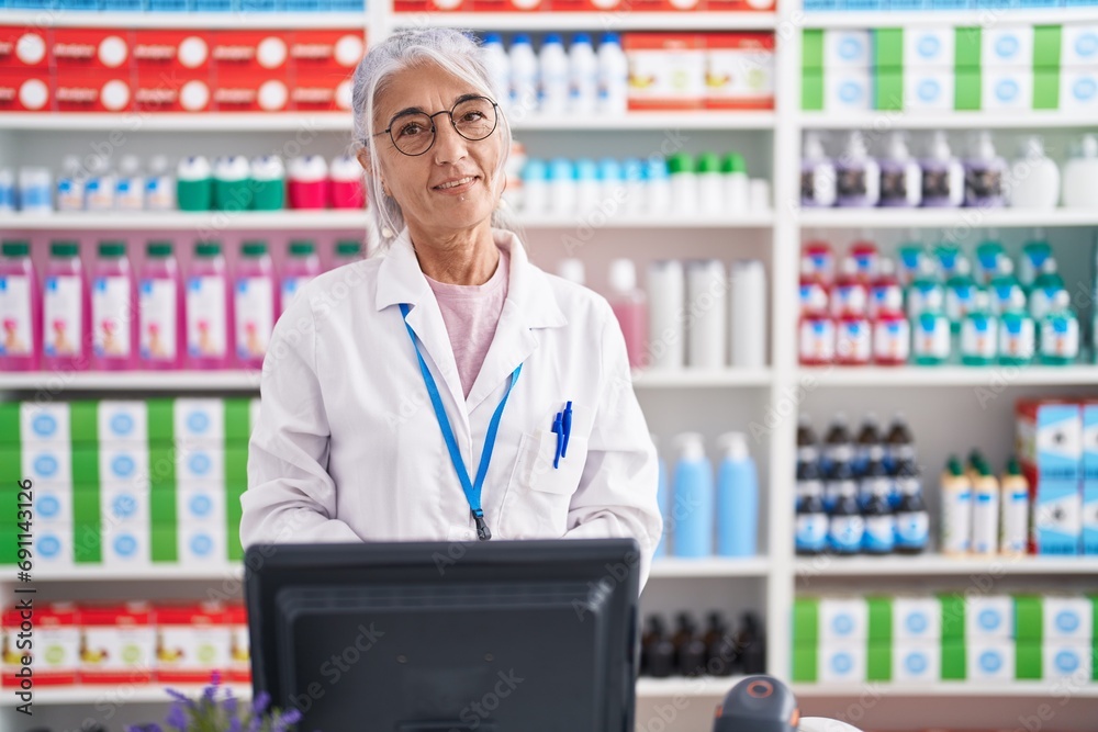 Middle age woman with tattoos working at pharmacy drugstore with hands together and crossed fingers smiling relaxed and cheerful. success and optimistic