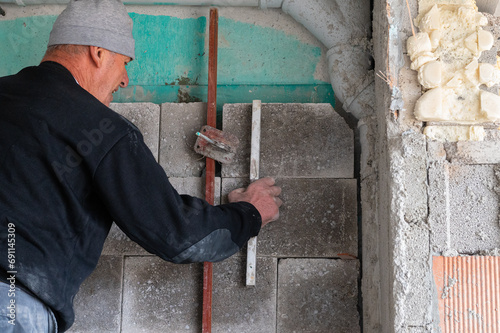 The builder is checking the evenness of the wall.