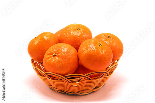 Ripe tangerine citrus, isolated tangerine orange in a wicker basket on a white background.