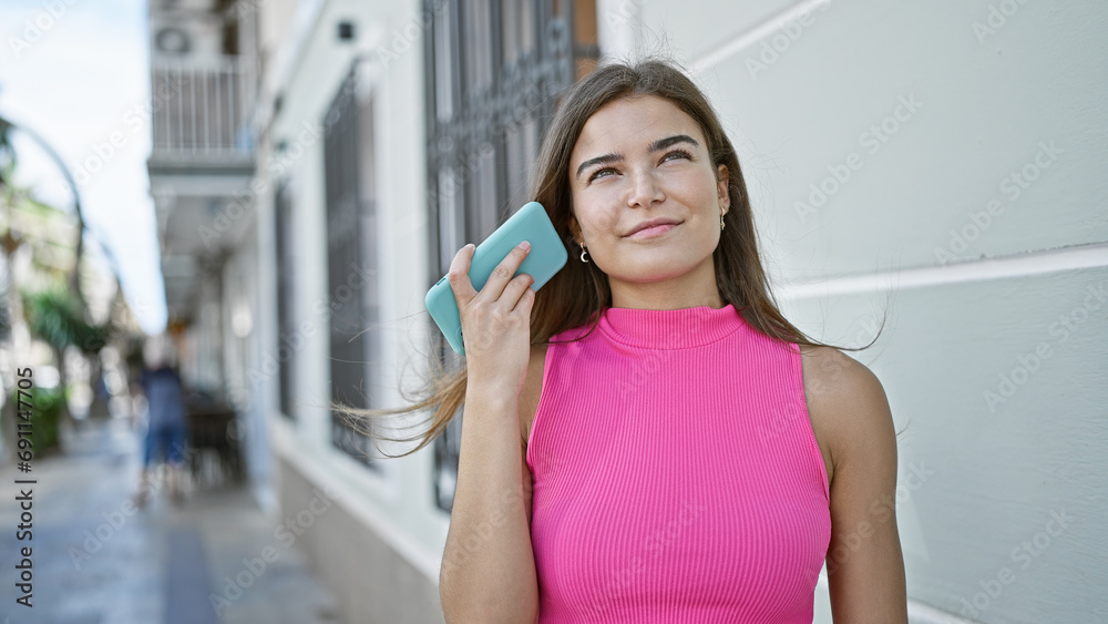 Young beautiful hispanic woman listening to voice message smiling at street