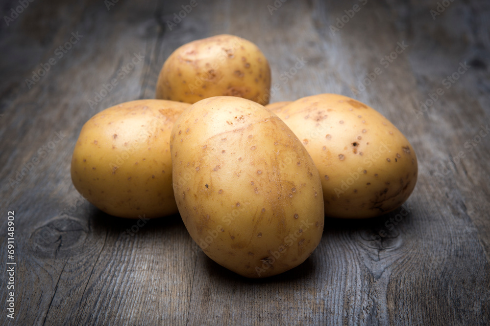 potatos in a pile on a wooden surface, uncooked potatos in a pile on a wooden surface, uncooked