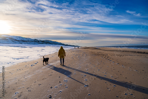 Spaziergänger mit Hund am Strand von Westerland auf Sylt im Winter