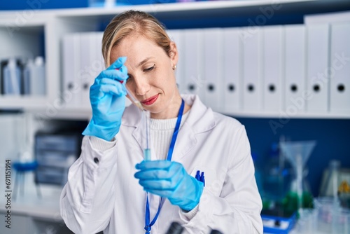 Fototapeta Naklejka Na Ścianę i Meble -  Young blonde woman scientist pouring liquid on test tube at laboratory