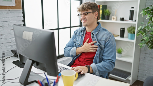 Fotografie Overworked handsome young hispanic man working at office business table, hurt by
