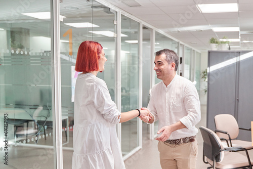 two workers in the office shaking hands in agreement or greeting.