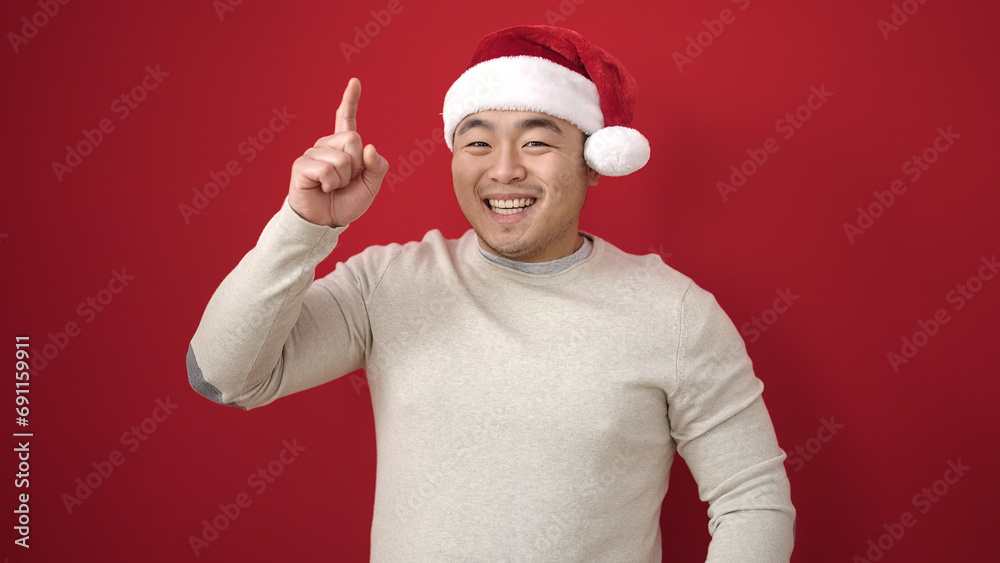 Young chinese man wearing christmas hat with idea expression over isolated red background Young chinese man wearing christmas hat with idea expression over isolated red background