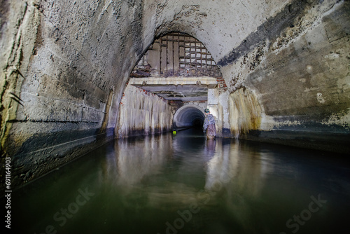 Man explores sewer tunnel or underground river © Mulderphoto
