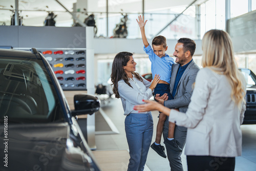 Family in a car dealership. Happy family came to an agreement with a car salesperson at a meeting in a showroom. Happy family choosing a new car in a showroom photo