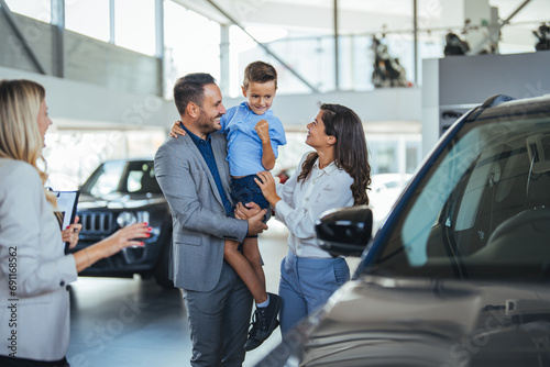Family in a car dealership. Happy family came to an agreement with a car salesperson at a meeting in a showroom. Happy family choosing a new car in a showroom