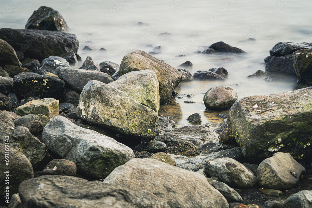 Cobblestones and rocks along the seacoast with smooth water through long exposure shot Cobblestones and rocks along the seacoast with smooth water through long exposure shot