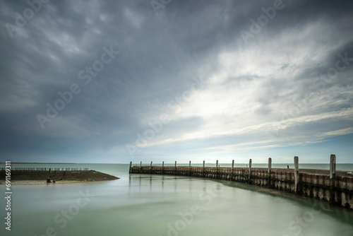 Wallpaper Mural Urbex harbor in a round shape of weathered concrete with rusted boolders and rotten mooring posts and above a threatening cloudy sky Torontodigital.ca