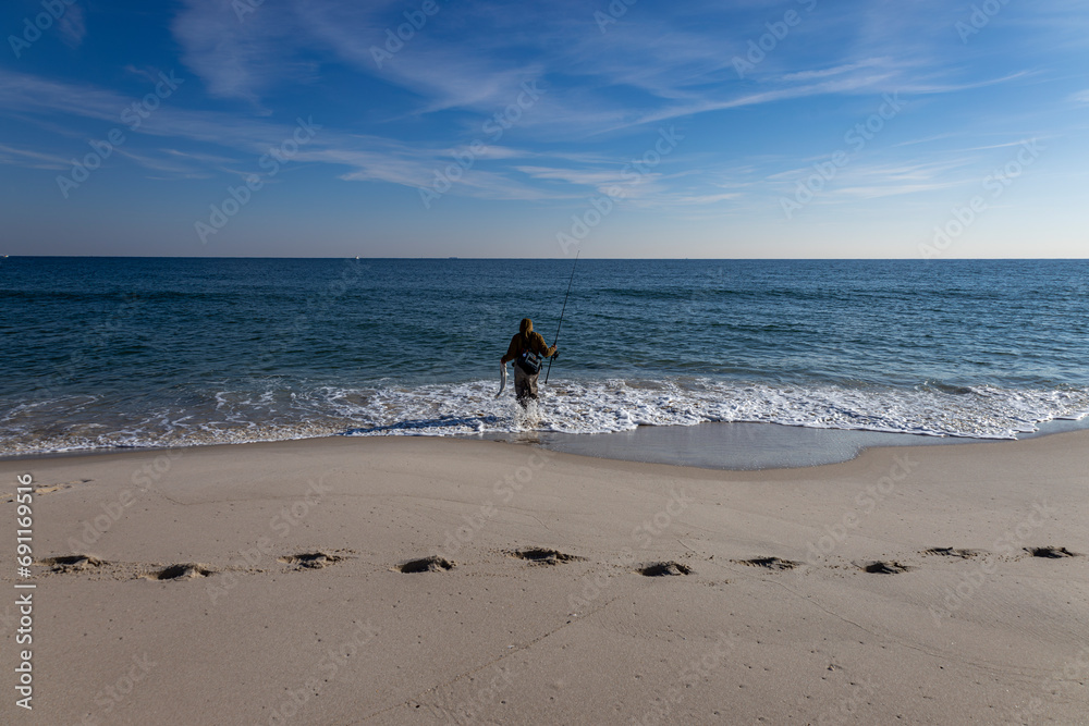 Surf Fisher Releasing Striped Bass Caught Surf Casting In New Jersey Surf Fisher Releasing Striped Bass Caught Surf Casting In New Jersey