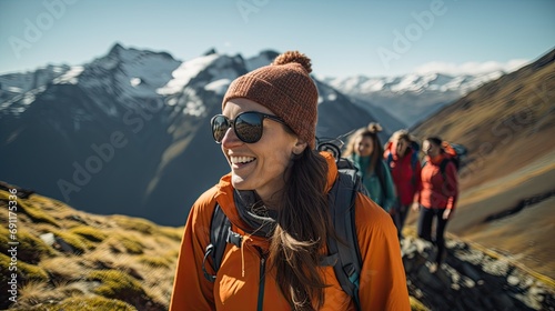 Group of hikers trekking in mountainous terrain, with a smiling woman in the foreground enjoying the adventure.