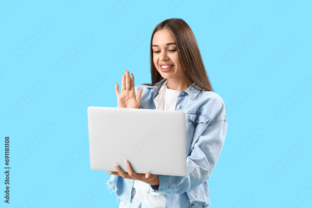 Young woman with laptop video chatting on blue background Young woman with laptop video chatting on blue background