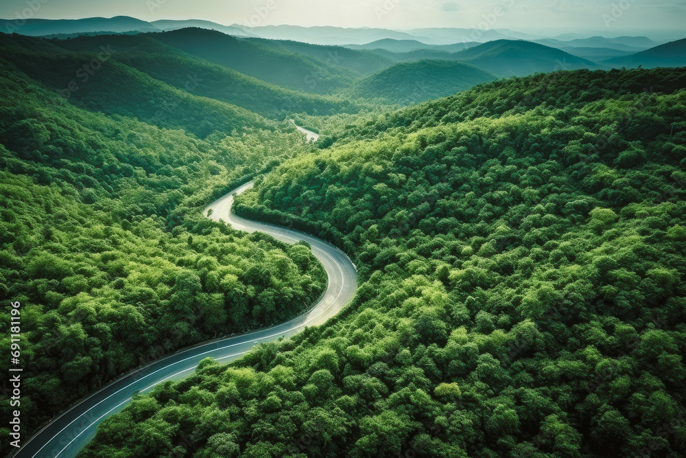 Aerial top view mountain road in dark green forest