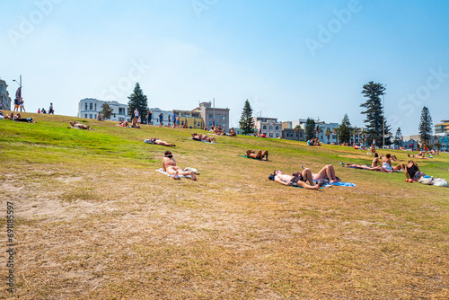 Sunbathers on the grass near Bondi Beach, a beautiful beach  with surfers, public and rock, with clear waters. Sydney, Australia, Dec 2019 © Wagner