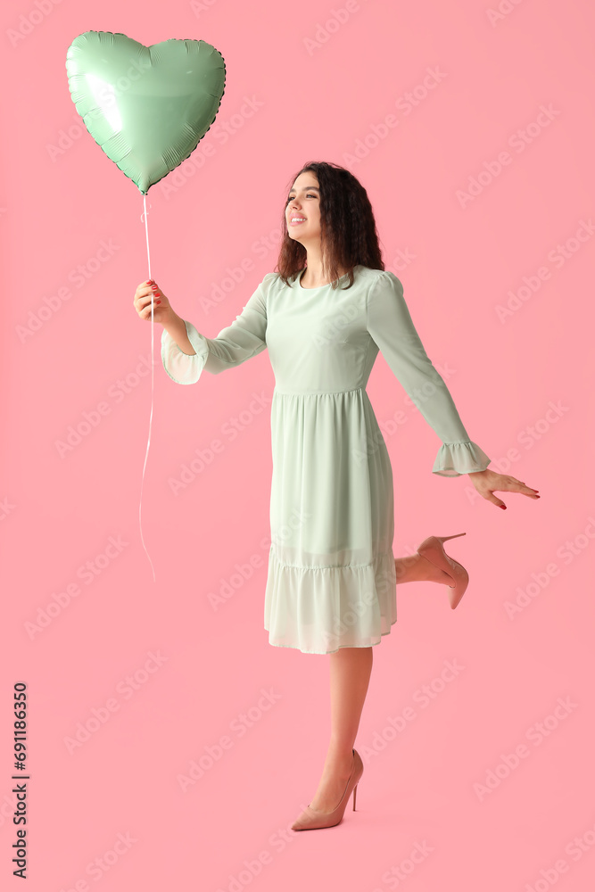 Beautiful young woman with heart shaped air balloon on pink background Beautiful young woman with heart shaped air balloon on pink background