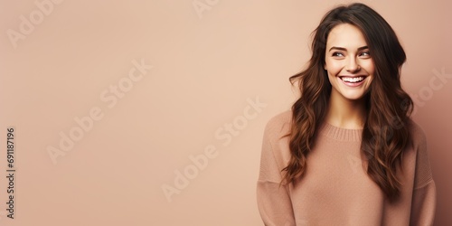 Portrait of a young latin woman with pleasant smile over beige backgroundl with copy space. Beautiful girl in warm sweater photo