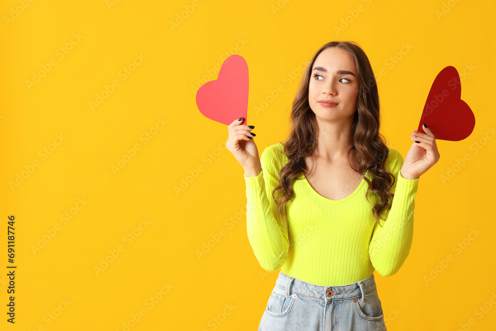 Beautiful young woman with red paper hearts on yellow background Beautiful young woman with red paper hearts on yellow background
