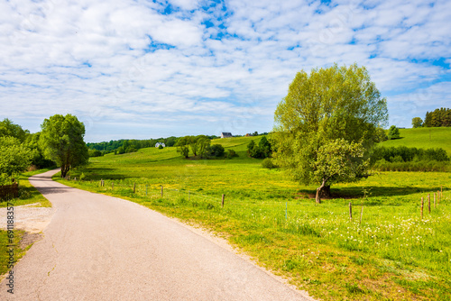 Rural road along farming fields In Suwalski Landscape Park during spring season, Podlasie, Poland