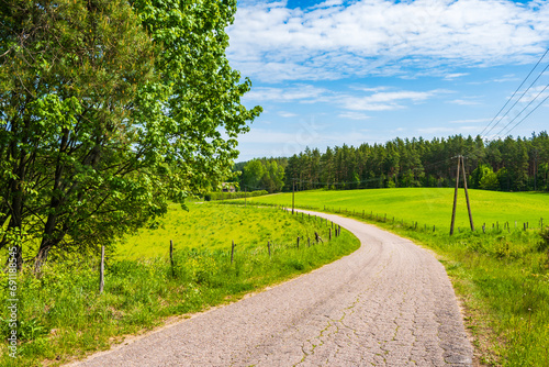 Rural road along farming fields In Suwalski Landscape Park during spring season, Podlasie, Poland